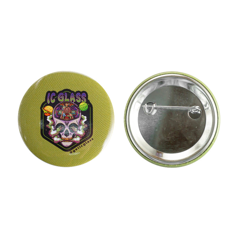 Two round pinback buttons on a white background, showing the front and back. The front button is olive green with a colorful graphic featuring a skull, sunglasses, and the text 'IC GLASS' and 'GETICGLASS'.
