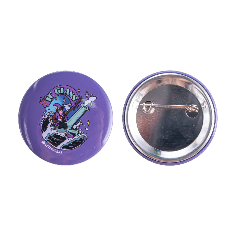 Two round pinback buttons on a white background, showing the front and back. The front button is purple with a cartoon graphic of a character riding a giant ship wheel, with the text 'GETICGLASS'.